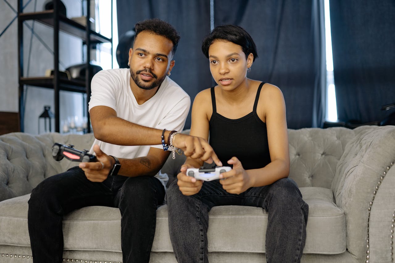 Two young adults enjoying video gaming together on a cozy couch at home.